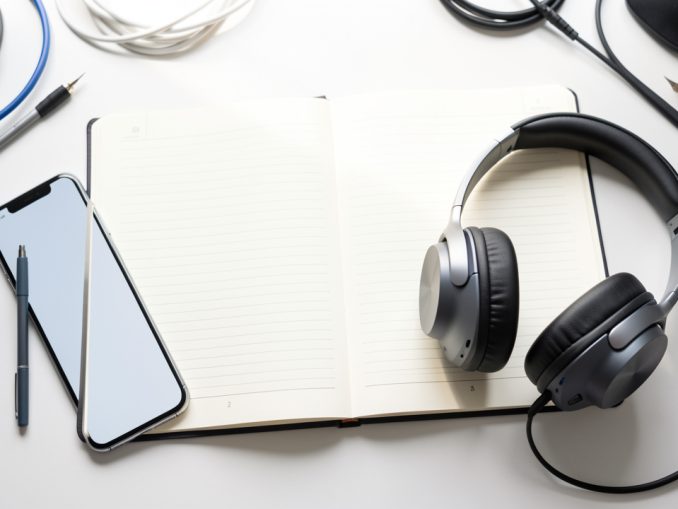Casque audio, smartphone et carnet ouverts sur un bureau d’étude lumineux, avec une ambiance inspirante et un éclairage doux.